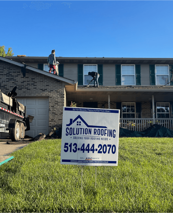 Roofers repairing roof with Solution Roofing sign